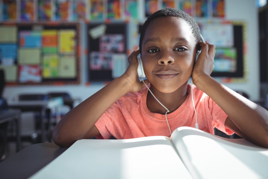 Boy listening music with headphones at desk